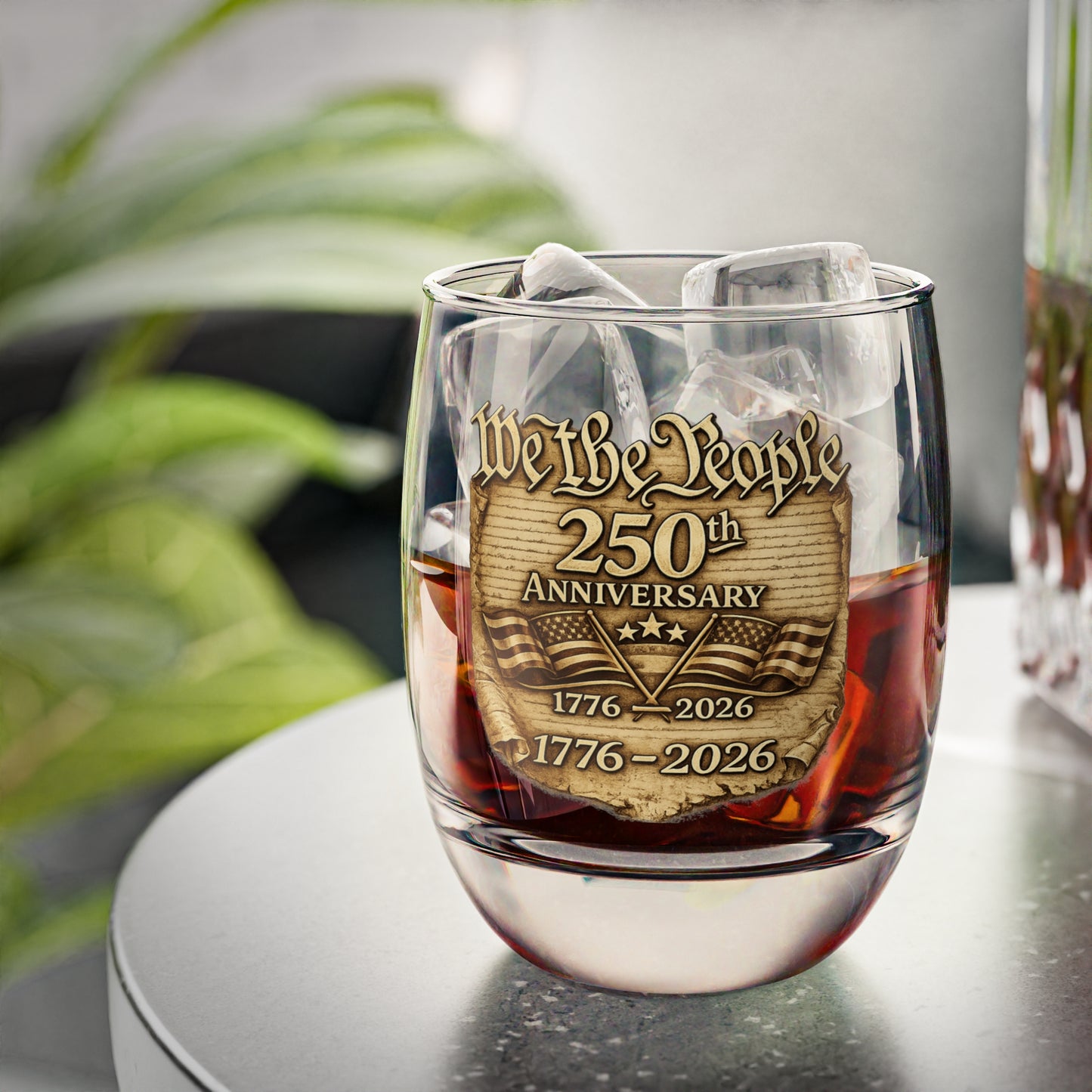 Whiskey glass with 'We the People' 250th Anniversary design filled with a dark liquid 