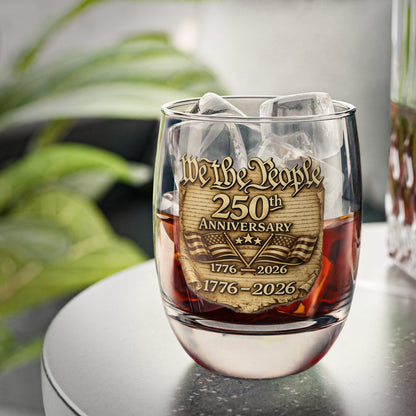 Whiskey glass with 'We the People' 250th Anniversary design filled with a dark liquid 