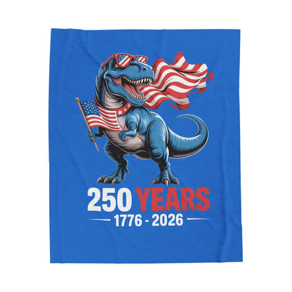 Blue blanket with a playful dinosaur holding American flags and '250 Years 1776-2026' text