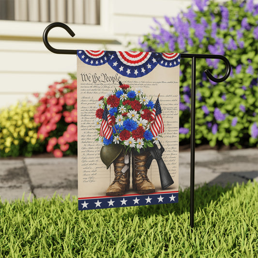 Decorative garden flag with boots, flowers, and American flags on a stand in front of flowers.