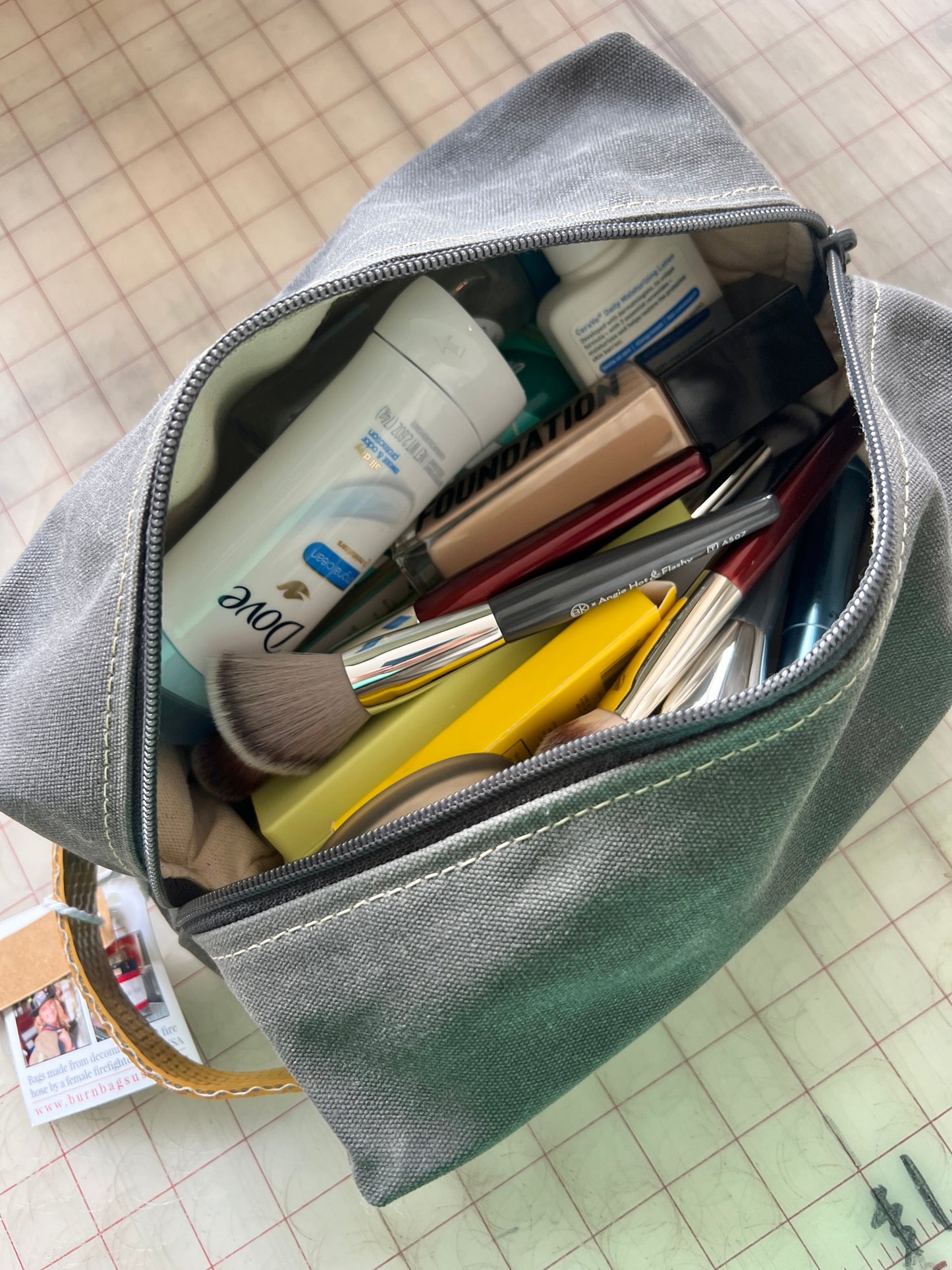 Top-down view of the Charcoal Gray Dopp Burn Bag unzipped, showing the lined interior filled with toiletries and travel items