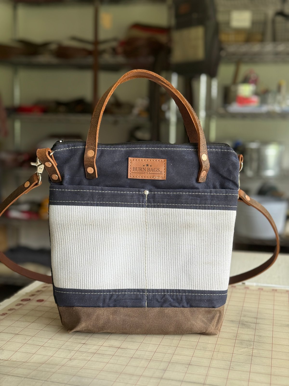 Navy Blue Engineer Burn Bag made from waxed canvas and decommissioned fire hose with leather handles and a detachable crossbody strap.