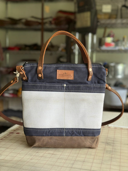 Navy Blue Engineer Burn Bag made from waxed canvas and decommissioned fire hose with leather handles and a detachable crossbody strap.