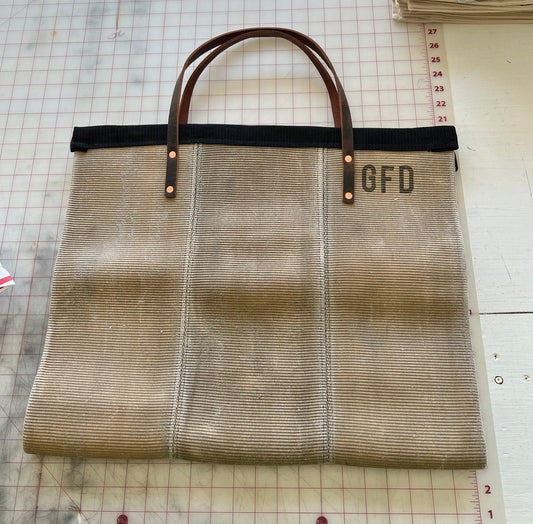 Fire Hose Wood Carrier made from decommissioned hose with sturdy handles and reinforced stitching.