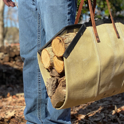 Fire Hose Wood Carrier loaded with firewood being carried outdoors, highlighting the durability of the decommissioned hose material and leather handles.